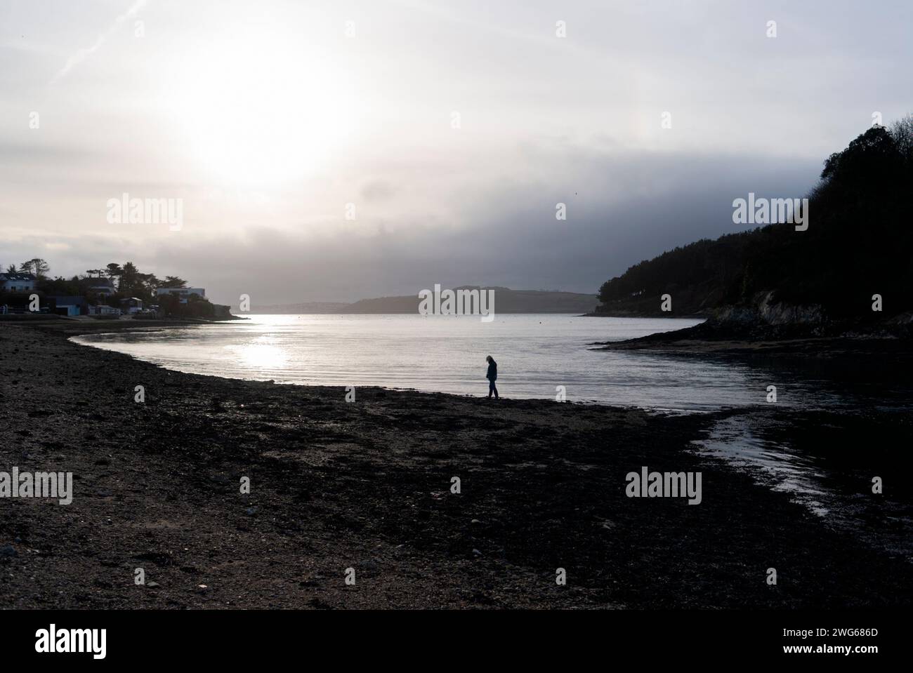 Eine Einzelfigur sucht bei Ebbe eine dramatische Mündungslandschaft nach interessanten Funden. Stockfoto