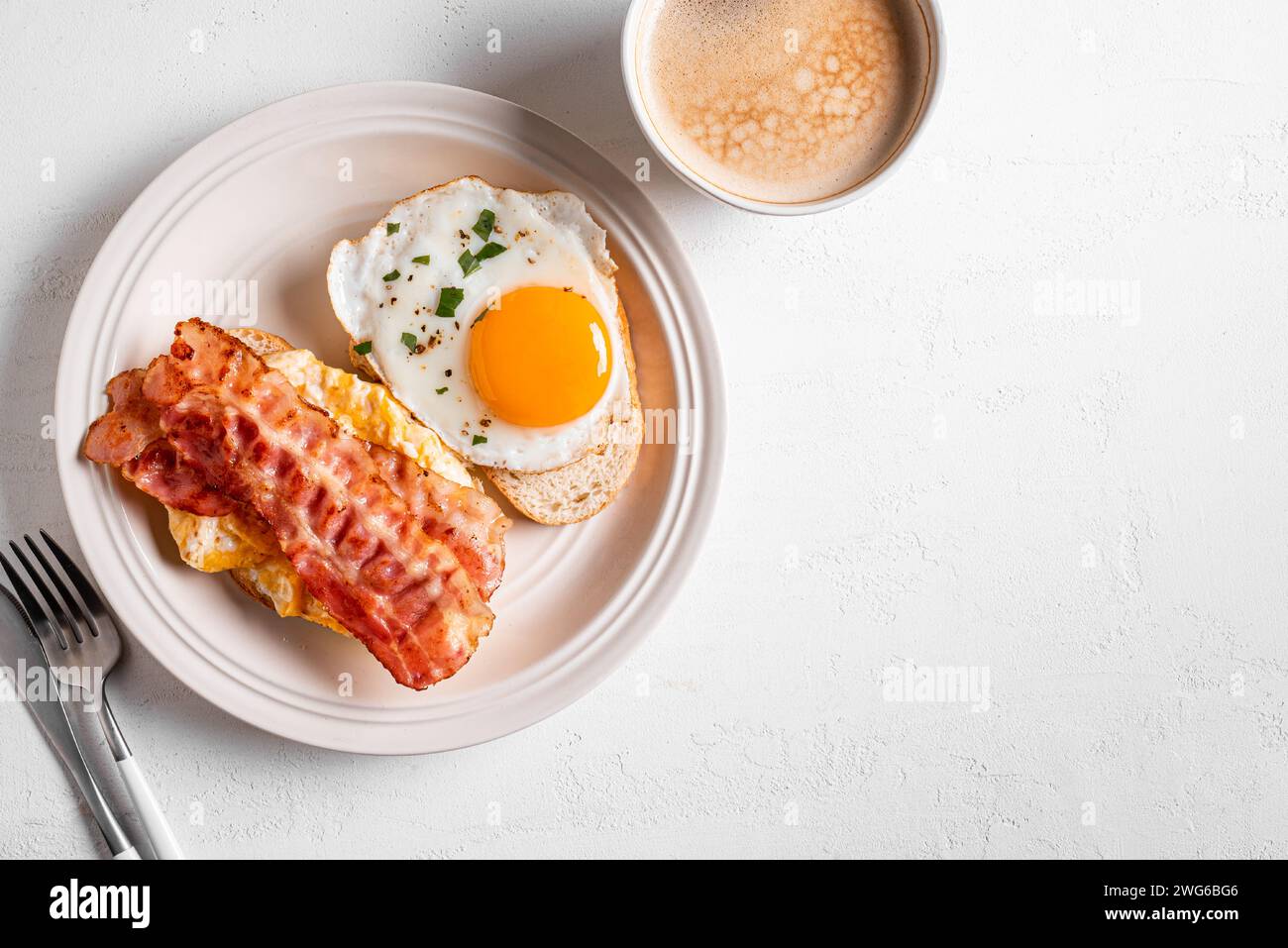 Frühstückssandwiches mit Spiegelei, Speck, Rührei und Tasse Kaffee, Kopierraum. Spiegeleier mit Speck auf Toast und Cappuccino am Morgen Stockfoto