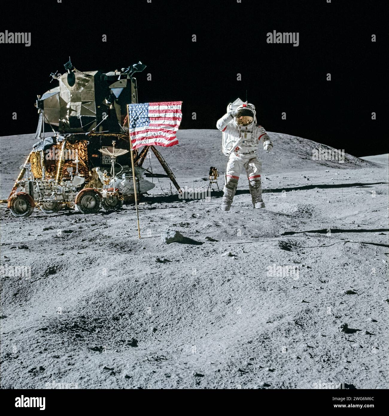 Apollo 16 Astronaut John W. Young grüßt, während er neben der amerikanischen Flagge neben dem Orion-Mondmodul springt, während die ferne Ultraviolettkamera/Spektrograph hinter ihm aufgestellt ist. Foto von Charles M. Duke Jr. bei ihrem ersten Mondspaziergang am 21. April 1972. Stockfoto