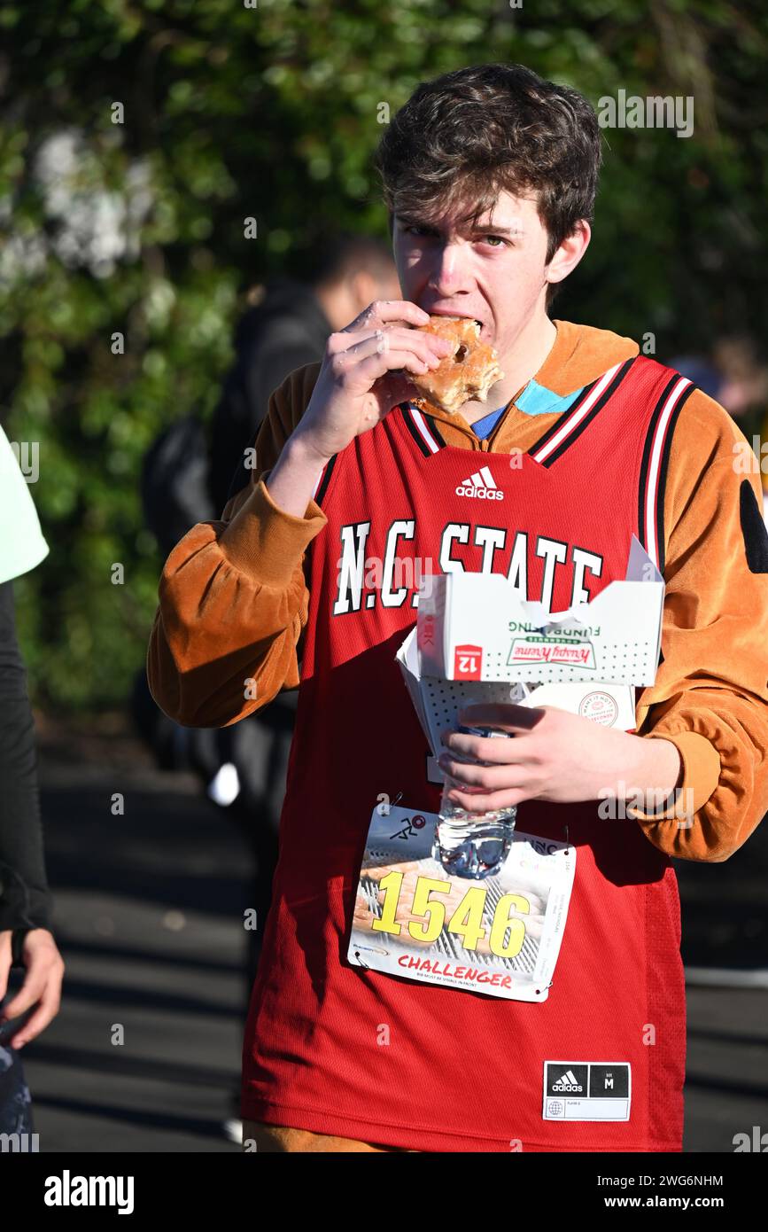 Raleigh, NC, USA, 3. Februar 2024. Ein Läufer hält an, um ein Dutzend glasierte Donuts auf halbem Weg des 20. Jährlichen Krispy Kreme Challenge 5-km-Rennens zu essen. Die diesjährige Veranstaltung, die 2004 erstmals als „Mut“ ausgetragen wurde, bot knapp über 4.000 Teilnehmer. Seit 2006 dient die Krispy Kreme Challenge als Spendenaktion für das University of North Carolina Children’s Hospital und sammelte über 2 Millionen US-Dollar. Credit D Guest Smith / Alamy Live News Stockfoto