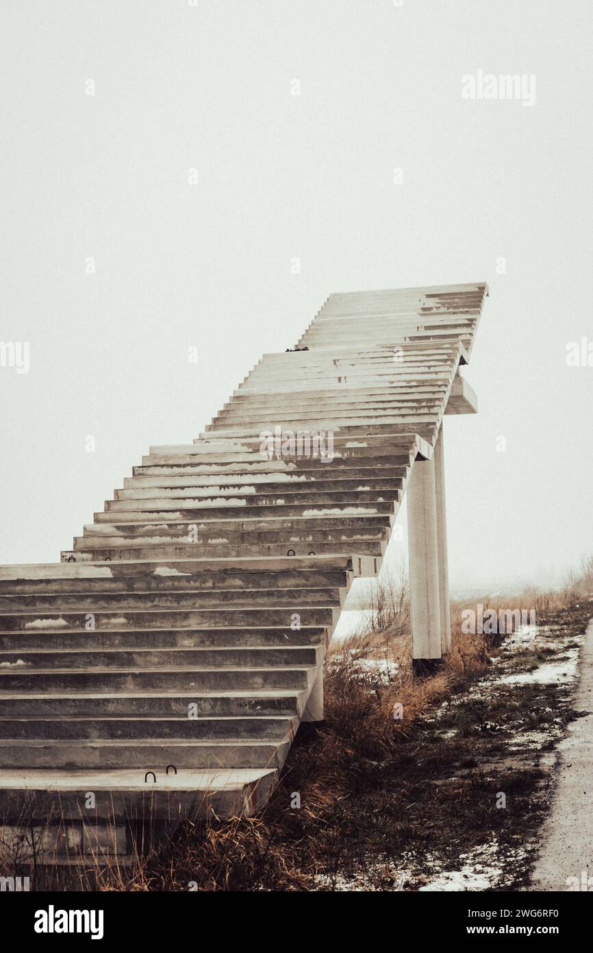 Treppen ins Nirgendwo. Leere unfertige Bridge. Außentreppe ohne Ende Treppe zum Himmel. Brücke im Bau. Treppen gegen bewölkten Himmel Stockfoto