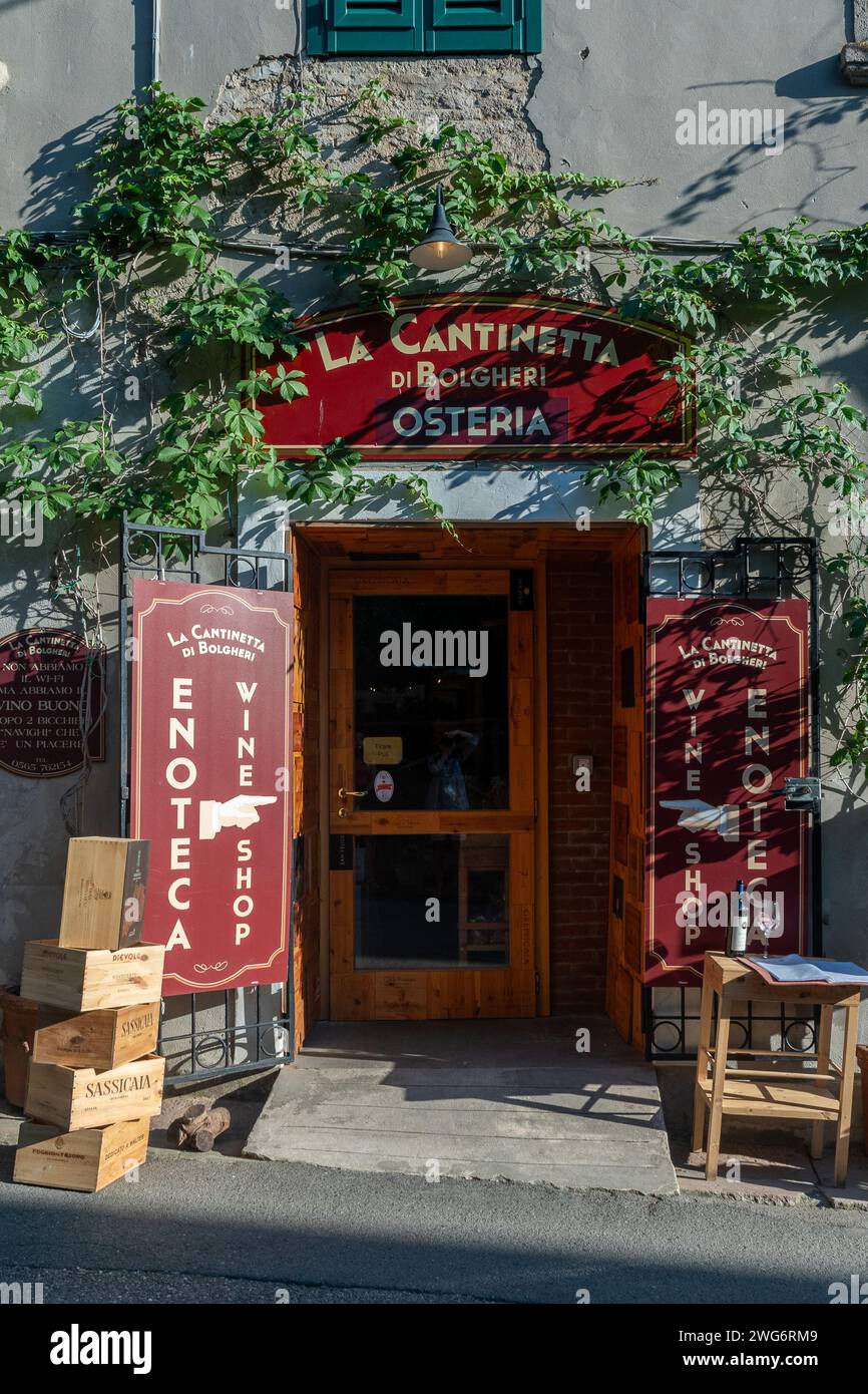 Vor einer typischen Taverne und Weinhandlung im mittelalterlichen Dorf auf den Hügeln der toskanischen Maremma, Bolgheri, Livorno, Toskana, Italien Stockfoto