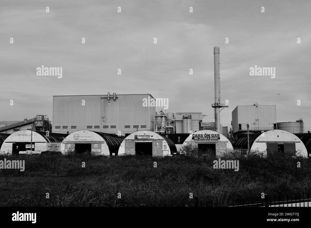 Barry, Vale of Glamorgan, Wales 2. Februar 2024: Bogenförmige, alte Industrieanlagen auf dem Hafengelände in der Nähe neuer Wohnbaustellen am Ufer Stockfoto