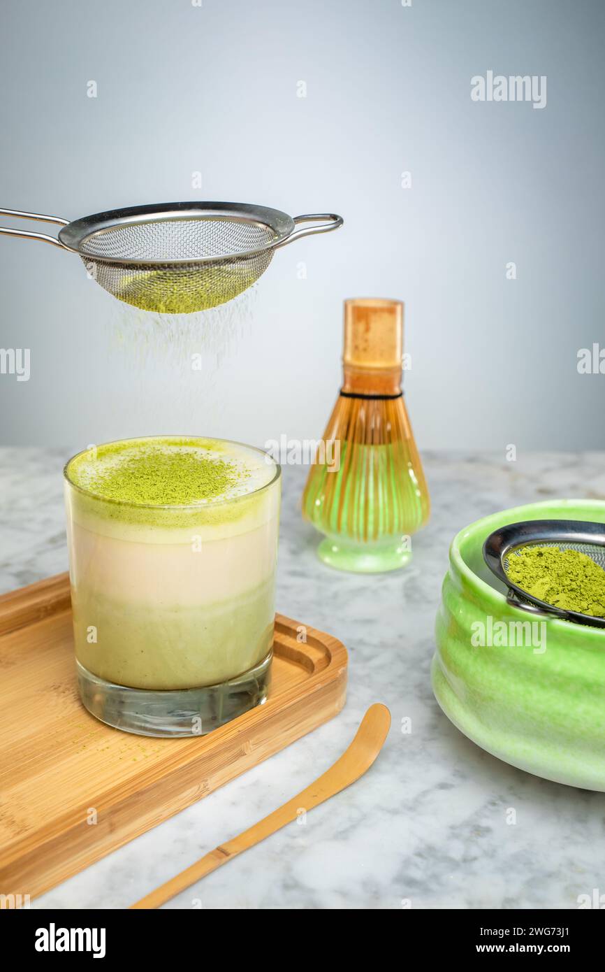 Eine Tasse grüner Matcha mit Pulver auf einem Holzbrett. Stockfoto