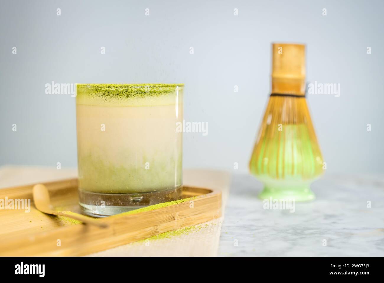 Eine Tasse grüner Matcha mit Pulver auf einem Holzbrett. Stockfoto