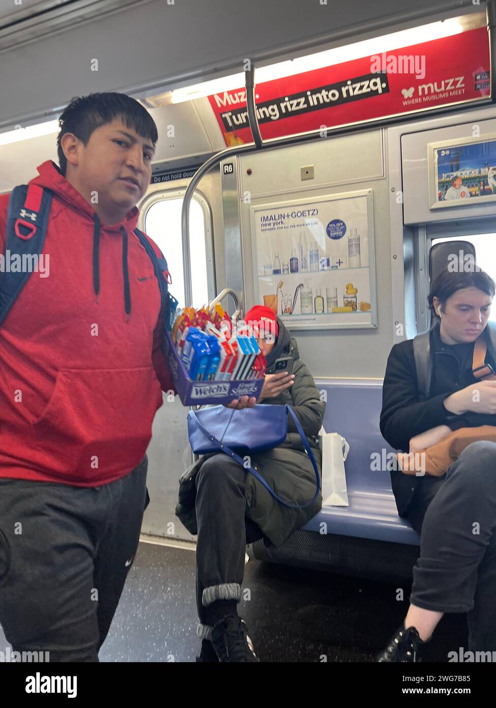 Ein nicht dokumentierter hispanischer Einwanderer versucht, ein paar Dollar mit dem Verkauf von Süßigkeiten in einem U-Bahn-Zug in Brooklyn, New York, zu verdienen. Stockfoto