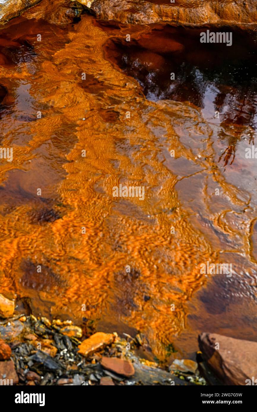 Der Rio Tinto in Huelva, Spanien, weist auffällige rote und orangene eisenreiche Ablagerungen und Spuren grüner Mikroorganismen auf Stockfoto