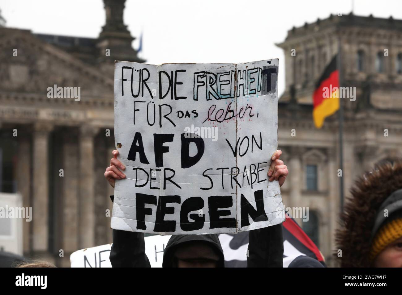 Berlin, Deutschland, 03.02.2024: Deutscher Bundestag: Demo gegen Rechtsextremismus von Netzwerk Hand in Hand , Menschenkette geplant: Demonstranten haben sich versammelt, eine Person hält ein Schild mit der Aufschrift für die Freiheit für das Leben, AfD von der Straße fegen , im Hintergrund das Reichstagsgebäude mit Deutschlandfahne *** Berlin, Deutschland, 03 02 2024 Demonstration des Deutschen Bundestages gegen Rechtsextremismus geplant von Hand in Hand Netzwerk , Menschenketten-Demonstranten haben sich versammelt, eine Person hält ein Schild mit der Aufschrift für Freiheit fürs Leben, fegt AfD von der Straße , in Stockfoto