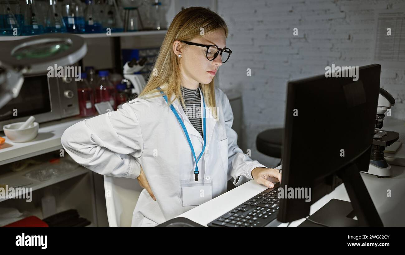 Fokussierte blonde Frau, die an einem Computer in einem Labor arbeitet und Gesundheit, Forschung und Technologie präsentiert. Stockfoto