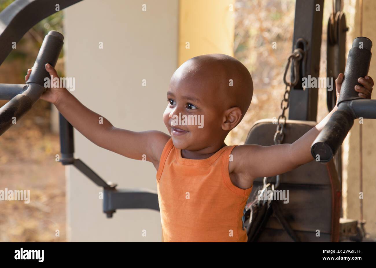 afroamerikaner, gemischtes Kleinkind, das draußen im Hof zu Hause in einem Fitnessgerät arbeitet Stockfoto