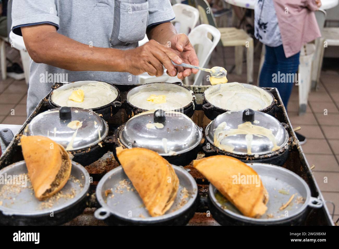 Anbieter, der traditionelle köstliche Apam balik oder Erdnuss-Pfannkuchen im Speisesaal zubereitet Stockfoto