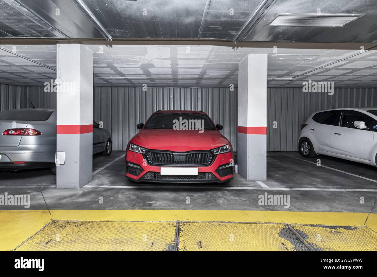 Eine Garage im Erdgeschoss eines Wohnhauses mit geparkten Fahrzeugen Stockfoto