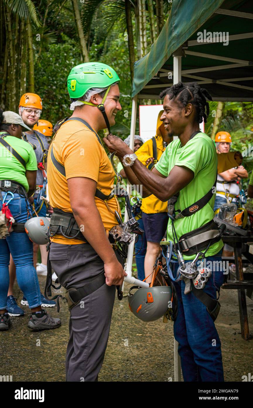 Ein Reiseleiter, der einen Gast auf eine Baumkronen-Tour vorbereitet, indem er die Sicherheitsausrüstung bei Rainforest Adventures, in der Nähe von Castries, St. Lucia, Januar 2024 überprüft. Stockfoto