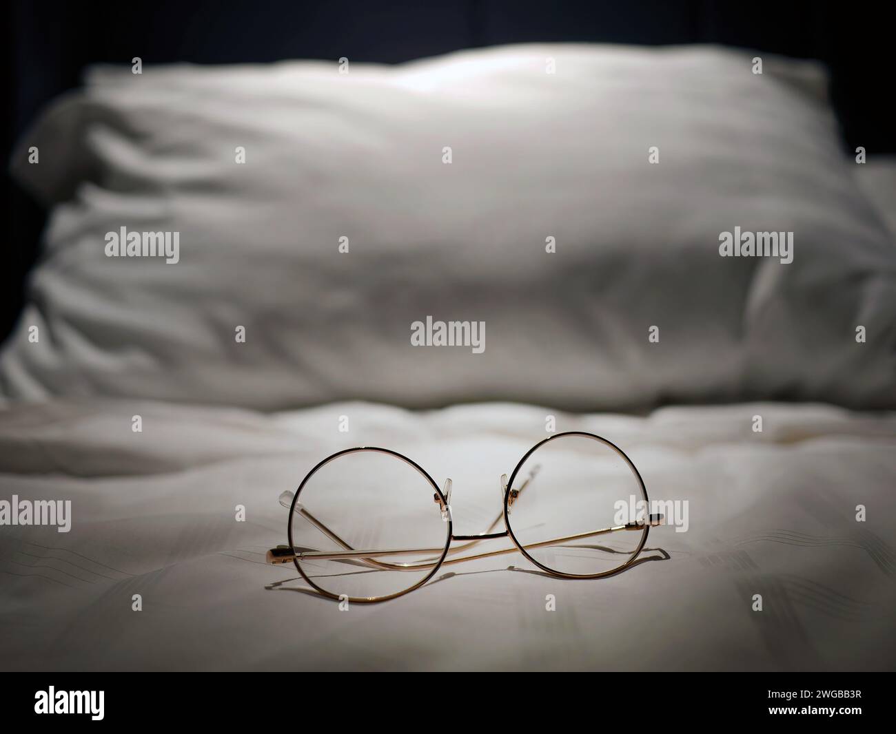 Eine Brillenoptik auf weißem Leinenbett, Nachtlicht, kurzsichtig, kurzsichtig, weitsichtig, Brillen, Business-Produkte, entspannen Sie sich oder ruhen Sie sich aus oder schlafen sie Stockfoto