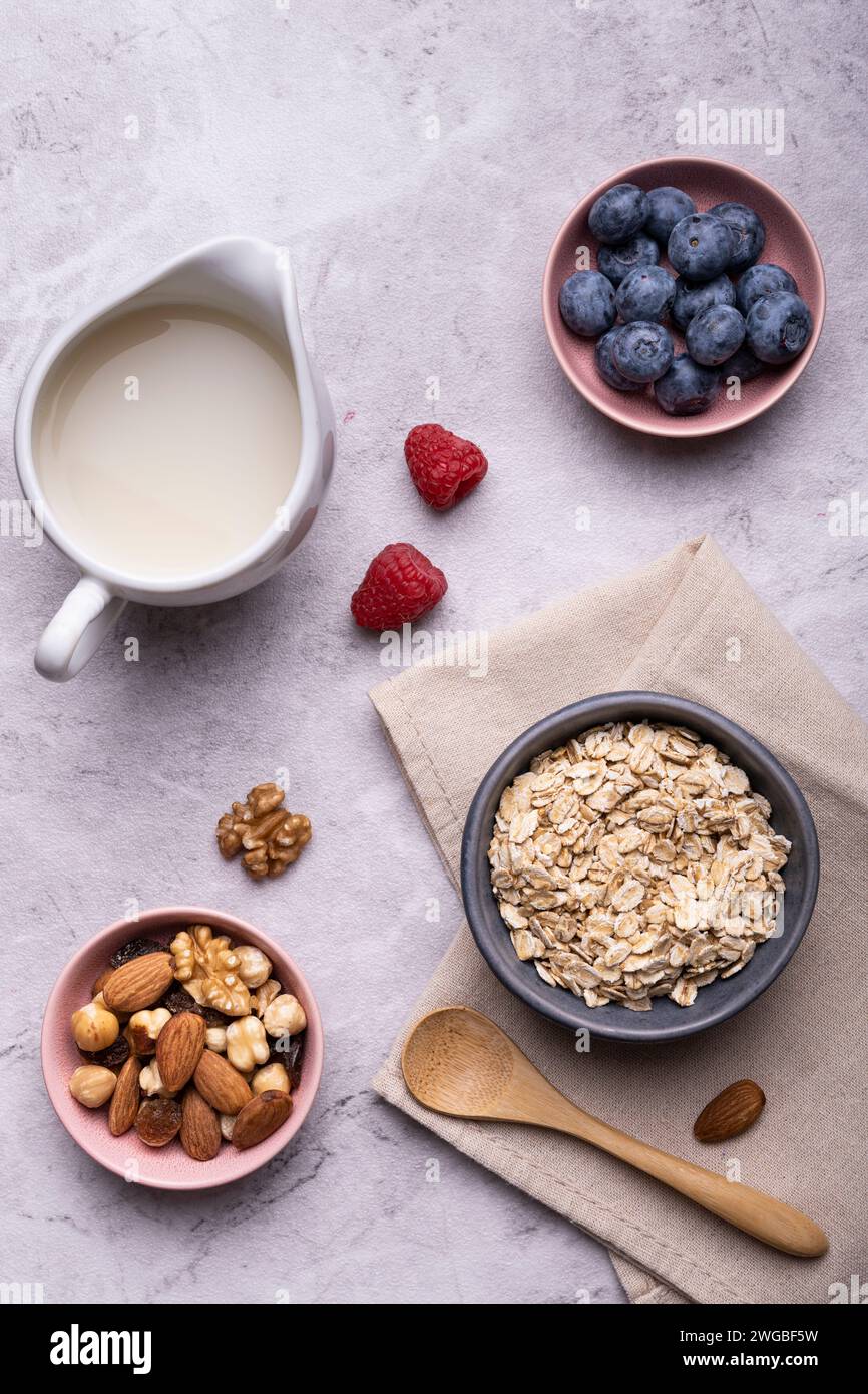 Konzept der gesunden Ernährung. Essen zum Frühstück, Blick von oben, eine Schüssel mit ganzen und Bio-Haferbrei, getrocknetem Obst, frischem Obst und Hafergetränk. Stockfoto