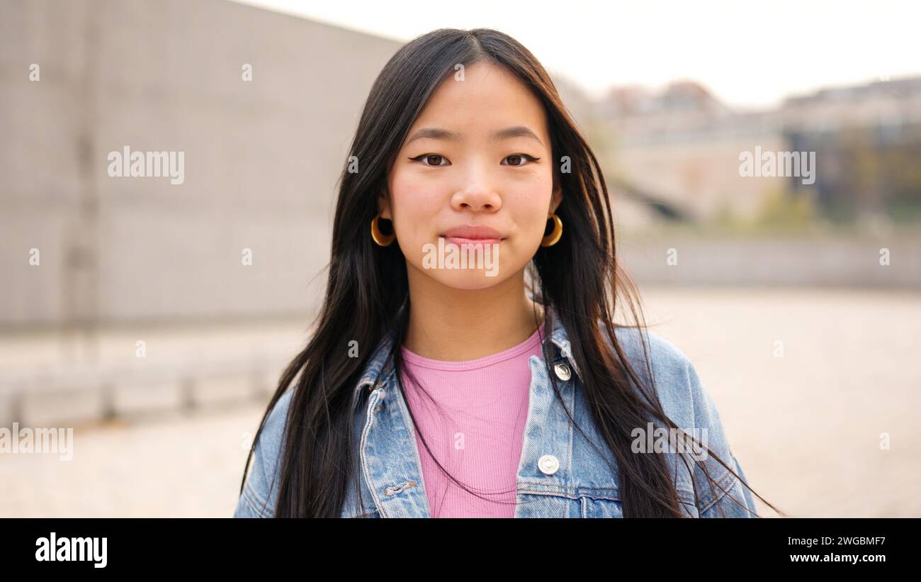 Asiatische junge Frau, die draußen in die Kamera schaut Stockfoto