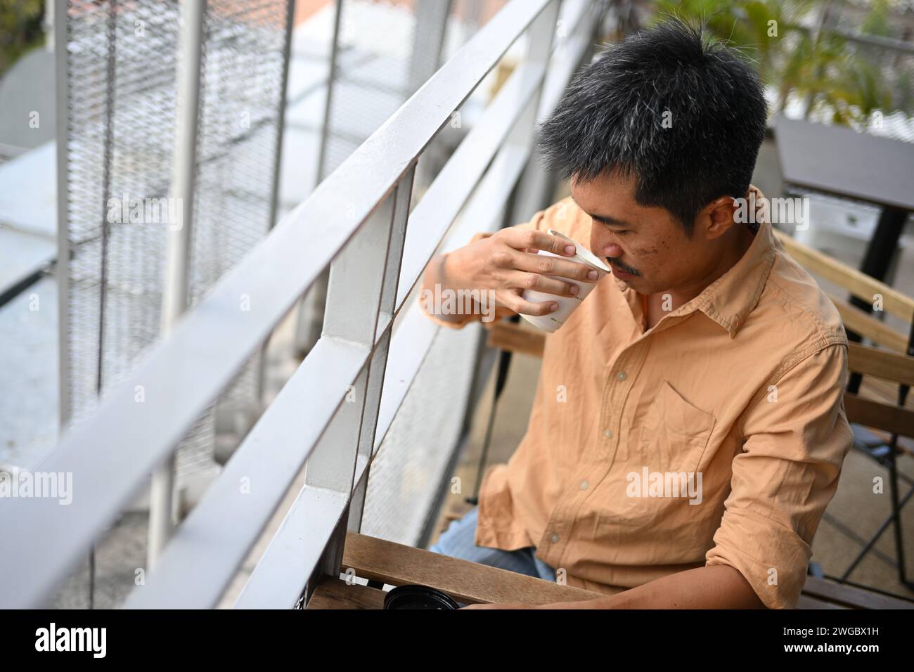 Mann, der in einem Café sitzt und ein heißes Getränk trinkt Stockfoto