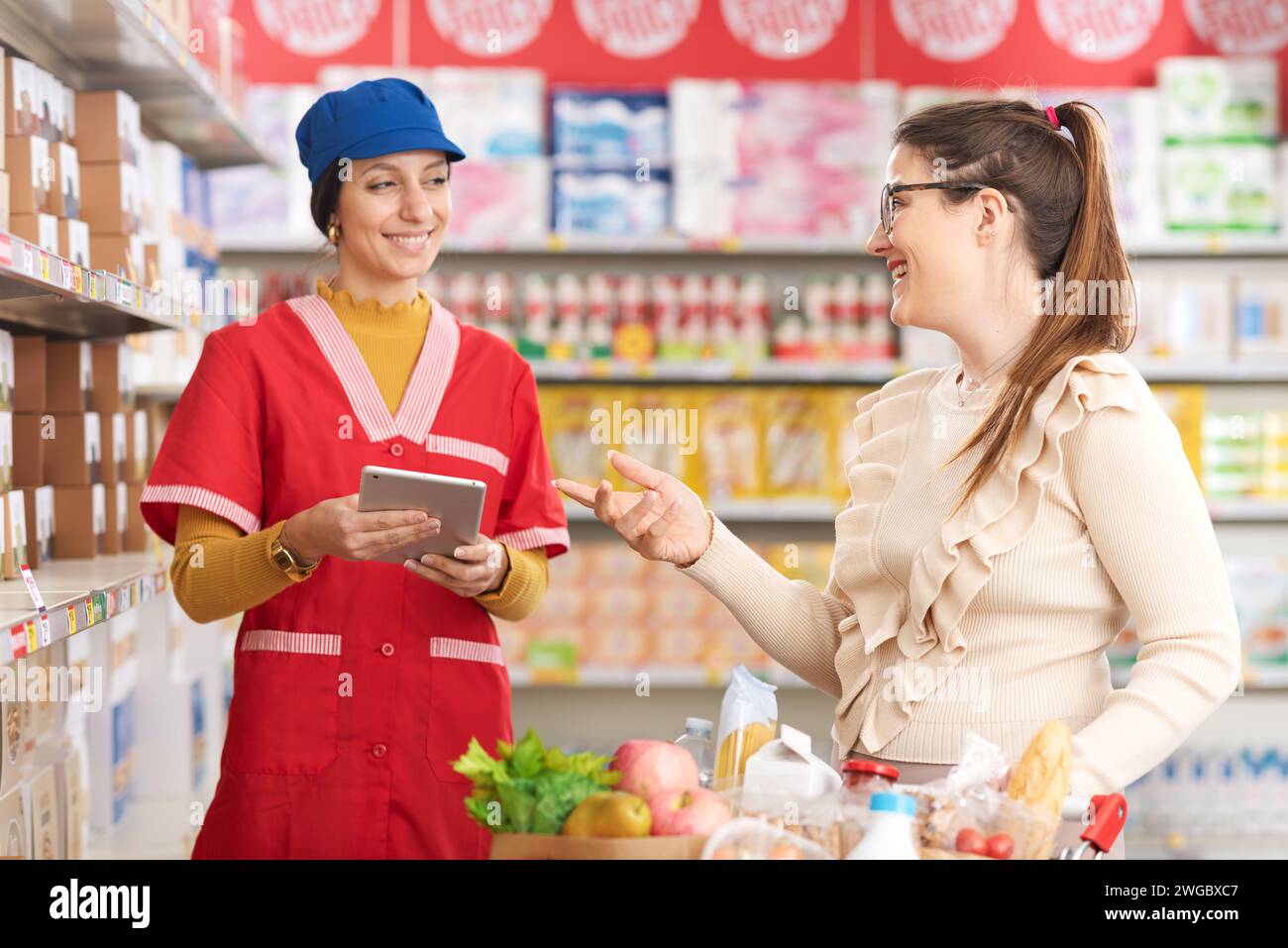 Ein freundlicher Lebensmittelkaufmann hilft einem Gast im Supermarkt, er redet und lächelt Stockfoto