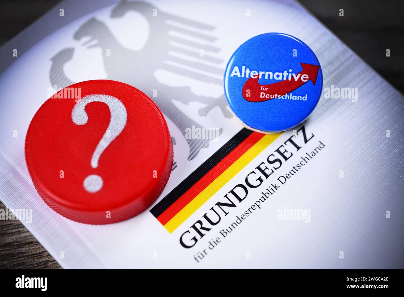 Parteianstecker der AfD und Fragezeichen auf dem deutschen Grundgesetz, Symbolfoto für die AfD-Verbotsdebatte *** AfD-Parteiabzeichen und Fragezeichen zur deutschen Verfassung, symbolisches Foto für die AfD-Verbotsdebatte Stockfoto