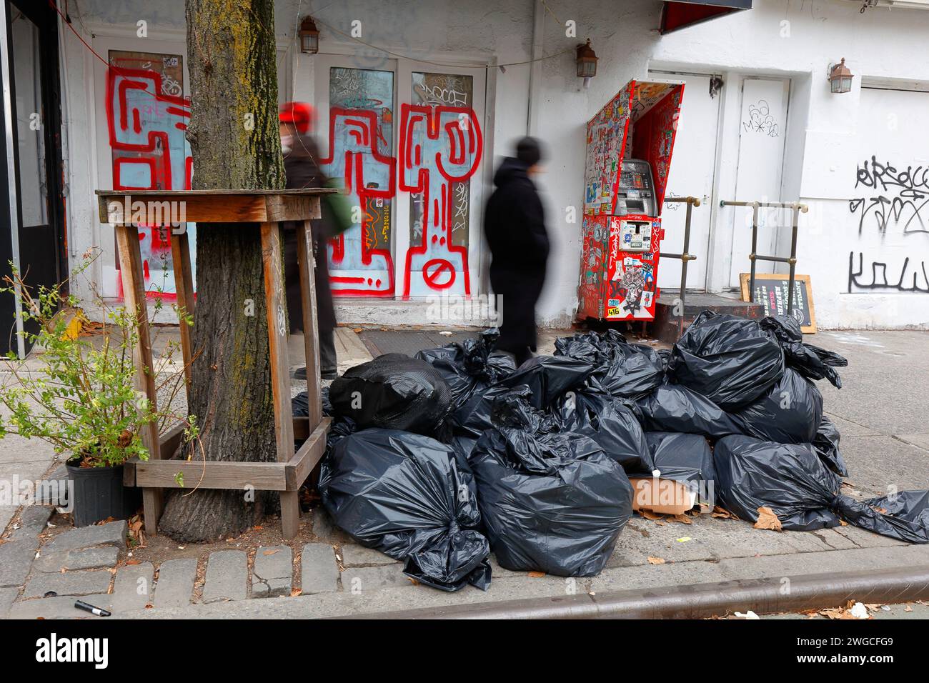 Im Januar 2024 laufen Leute an Müllsäcken und einem geschlossenen Unternehmen vorbei, das mit Graffiti verwüstet wurde. Stockfoto