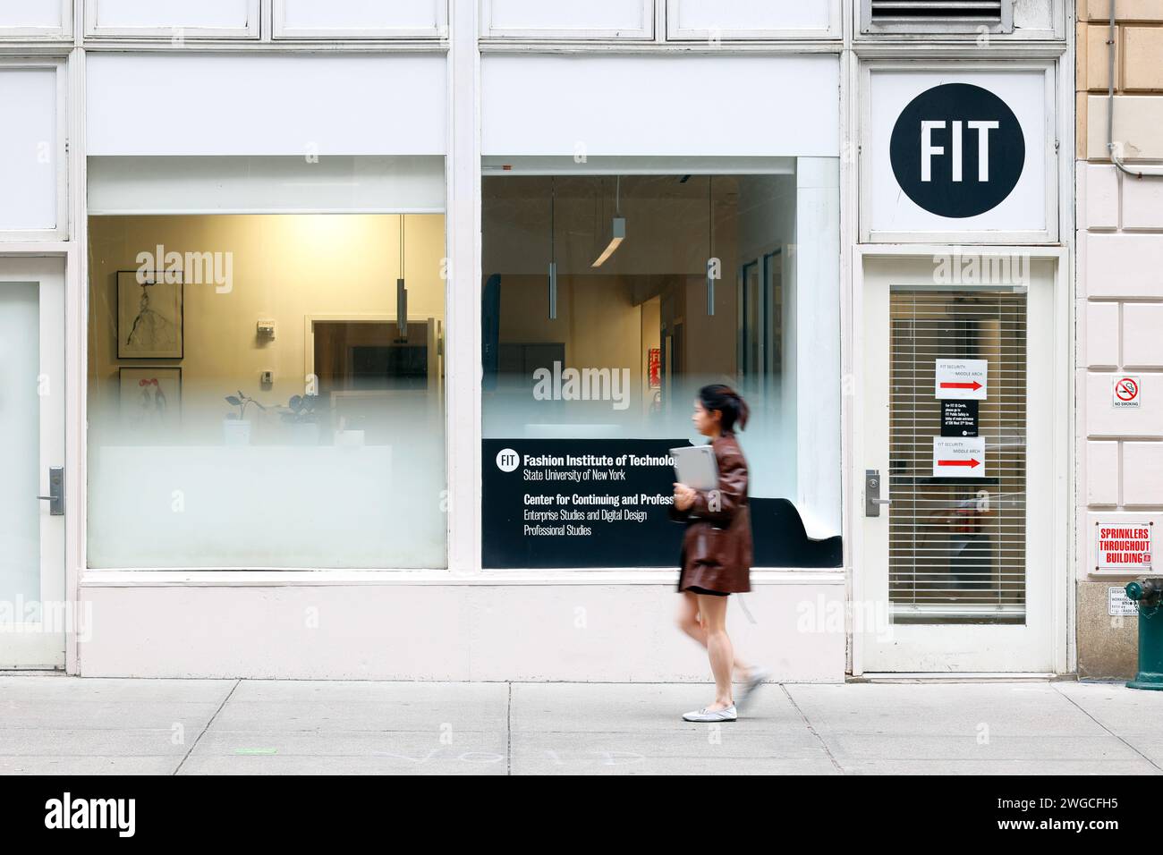 Eine Person läuft am Büro des Fashion Institute of Technology Center for Continuing and Professional Studies in Midtown Manhattan, New York City, vorbei Stockfoto
