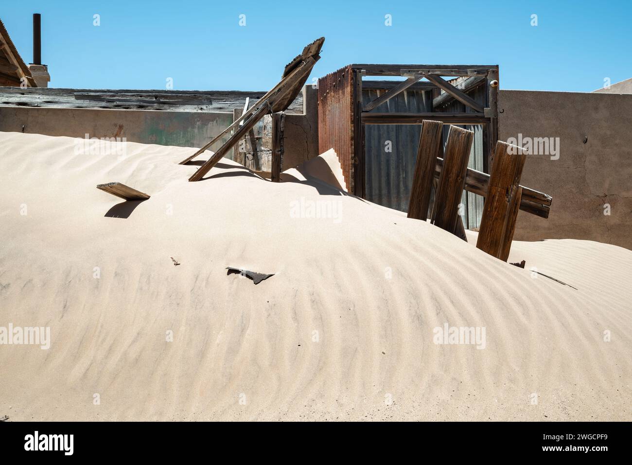 Verderbtes Gebäude in der Sandwüste mit verwitterter Holztür Stockfoto