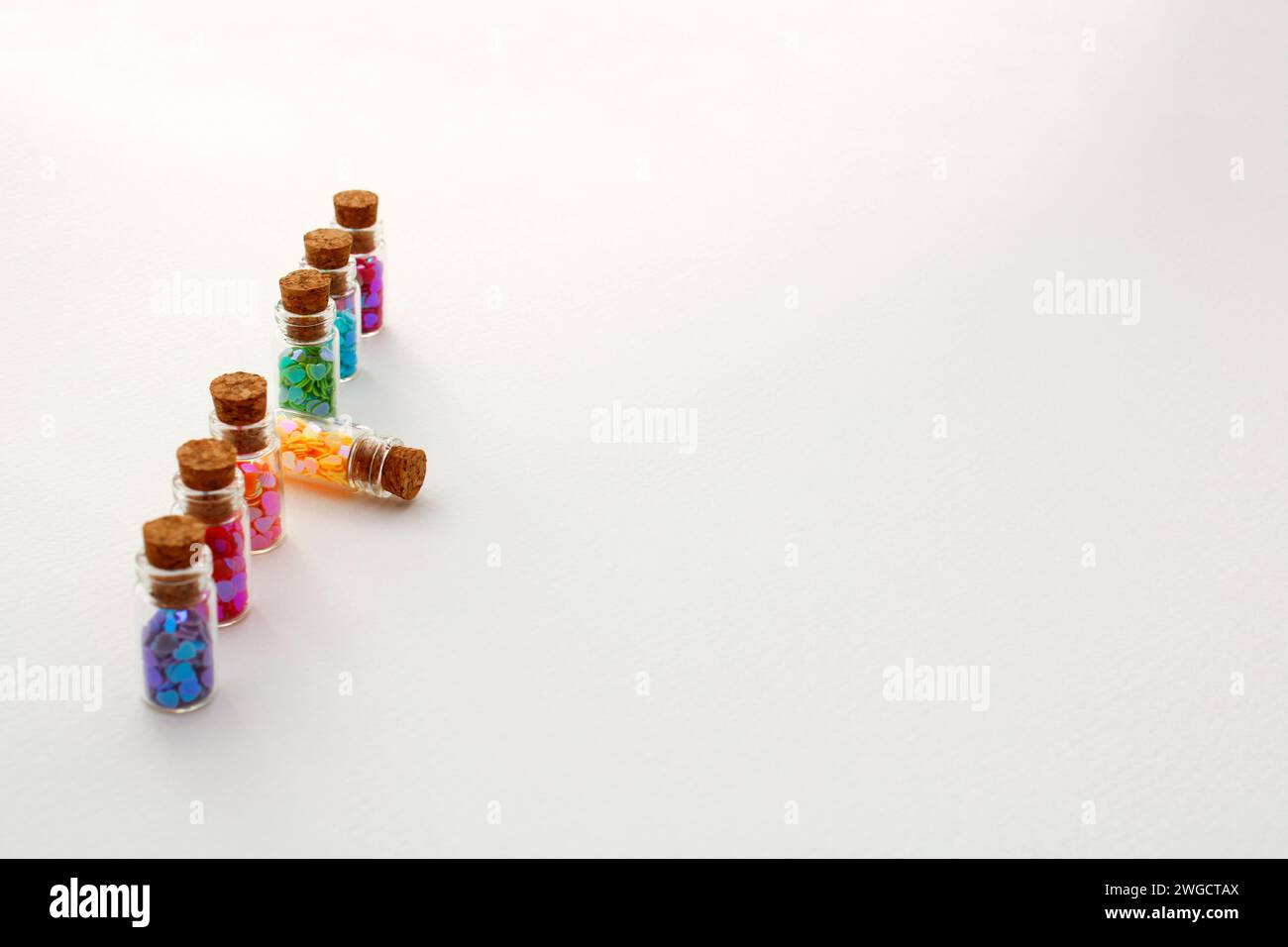 Reihe von Glasflaschen mit Herzen verschiedener Farben, wo eine davon herausragt Stockfoto