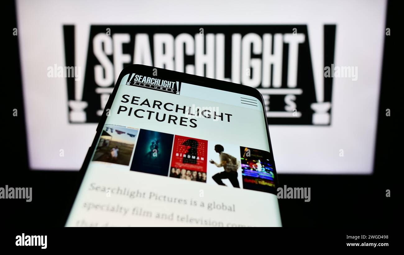 Mobiltelefon mit Website der US-amerikanischen Filmproduktionsfirma Searchlight Bilder vor dem Firmenlogo. Fokussieren Sie sich oben links auf der Telefonanzeige. Stockfoto