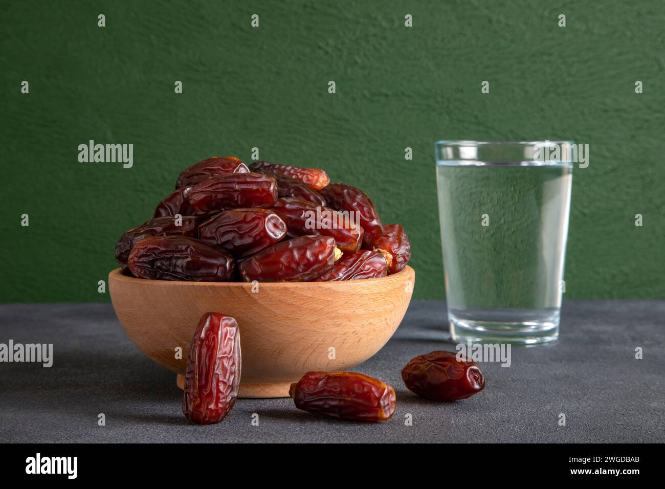 Traditioneller iftar-Tisch mit Datteln und einem Glas Wasser vor grünem Hintergrund Stockfoto