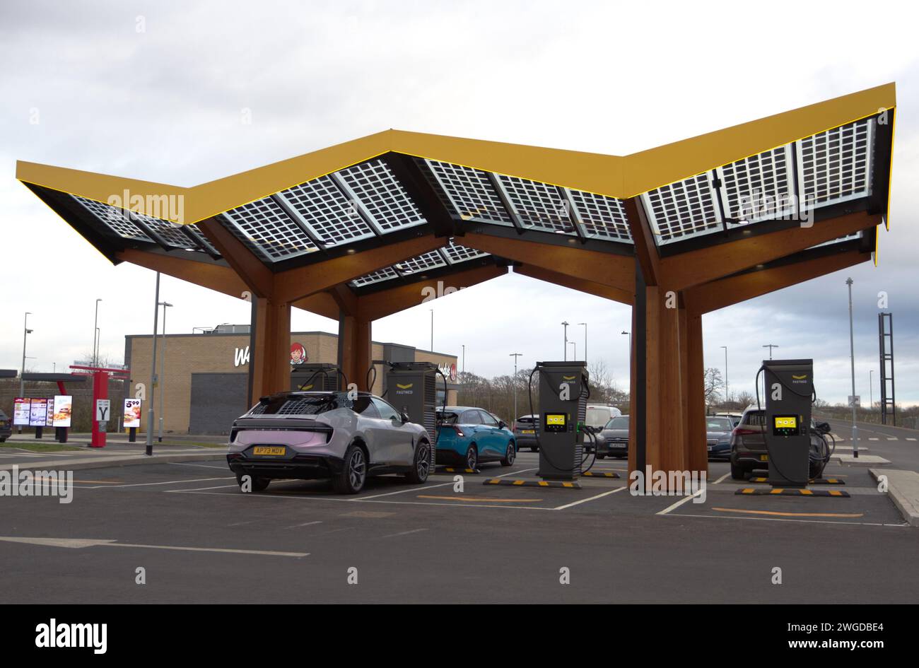 Autos mit einer Fastned Ladestation am Northern Gateway, Colchester. Fastned bietet superschnelles Laden von Elektrofahrzeugen Stockfoto