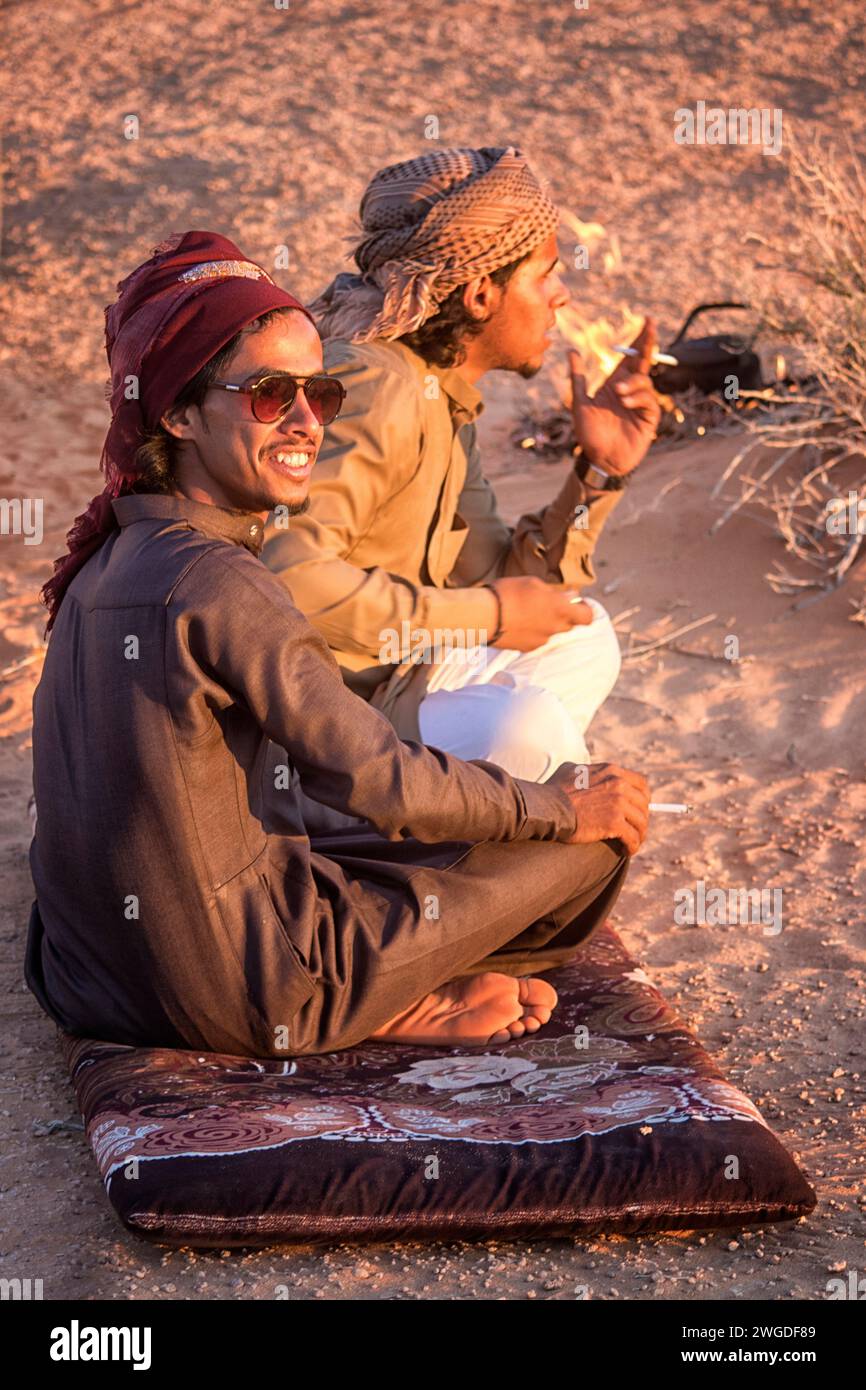 Zwei männliche beduinen sitzen und rauchen in der Wüste von Wadi Rum. Wādī Ramm (auch Wādī al-Ramm), auch bekannt als Tal des Mondes (arabisch وادي القمر Wādī al-Qamar), ist ein in Sandstein und Granitfelsen gehauenes Tal im Süden Jordaniens, nahe der Grenze zu Saudi-Arabien und etwa 60 km östlich der Stadt Aqaba. Es ist das größte Wadi in Jordanien. Stockfoto