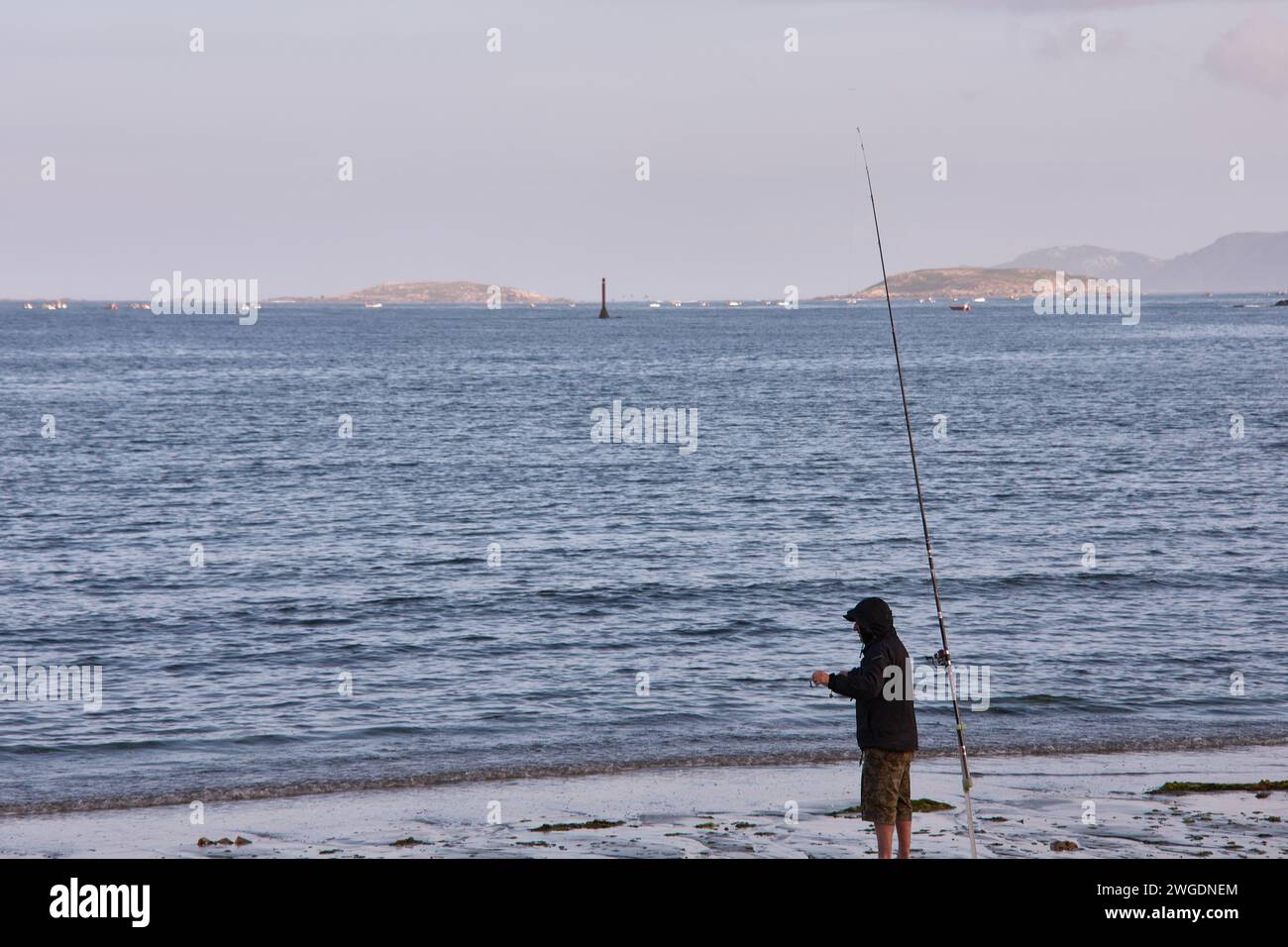 BAIONA, PONTEVEDRA, SPANIEN; Juli 2021: UN pescador en la Playa de la ladeira en baiona esperando para ver si pican los peces Stockfoto