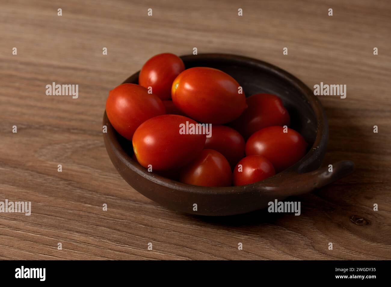 Pflaumentomaten in einer Tonschale auf dem Tisch Stockfoto