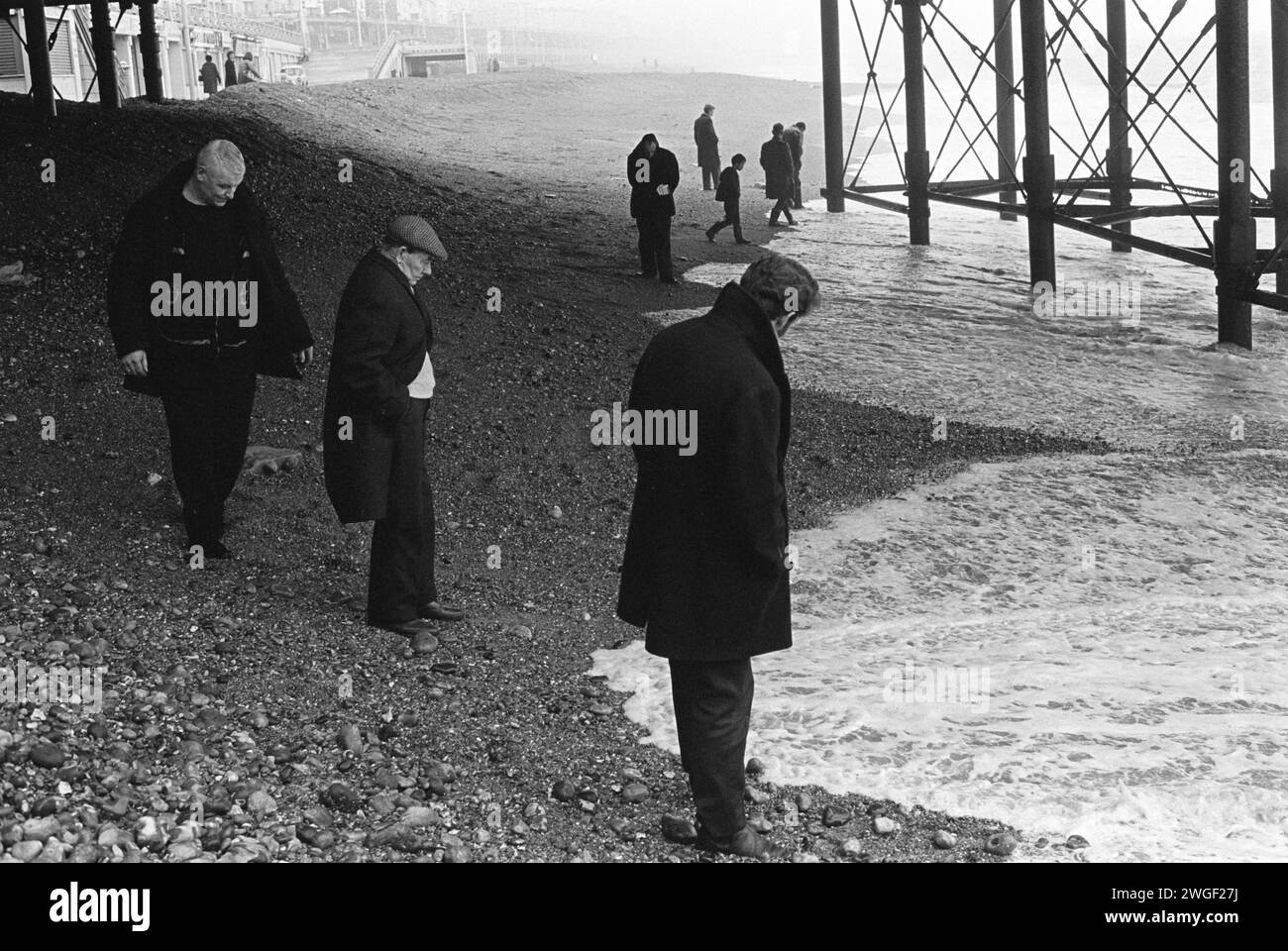 Strandkämmen unter dem Brighton Pier. Eine Gruppe von Männern am Strand wartet auf Geldmünzen, die mit der Flut gespült werden. Münzen, die nach einem geschäftigen Samstag durch den Lattenboden des Piers gefallen waren. Strandbewohner treffen sich am Sonntagmorgen. Manchmal auch als Blacksanding bekannt. Brighton, East Sussex, England, 1970 1980er Jahre Großbritannien HOMER SYKES Stockfoto