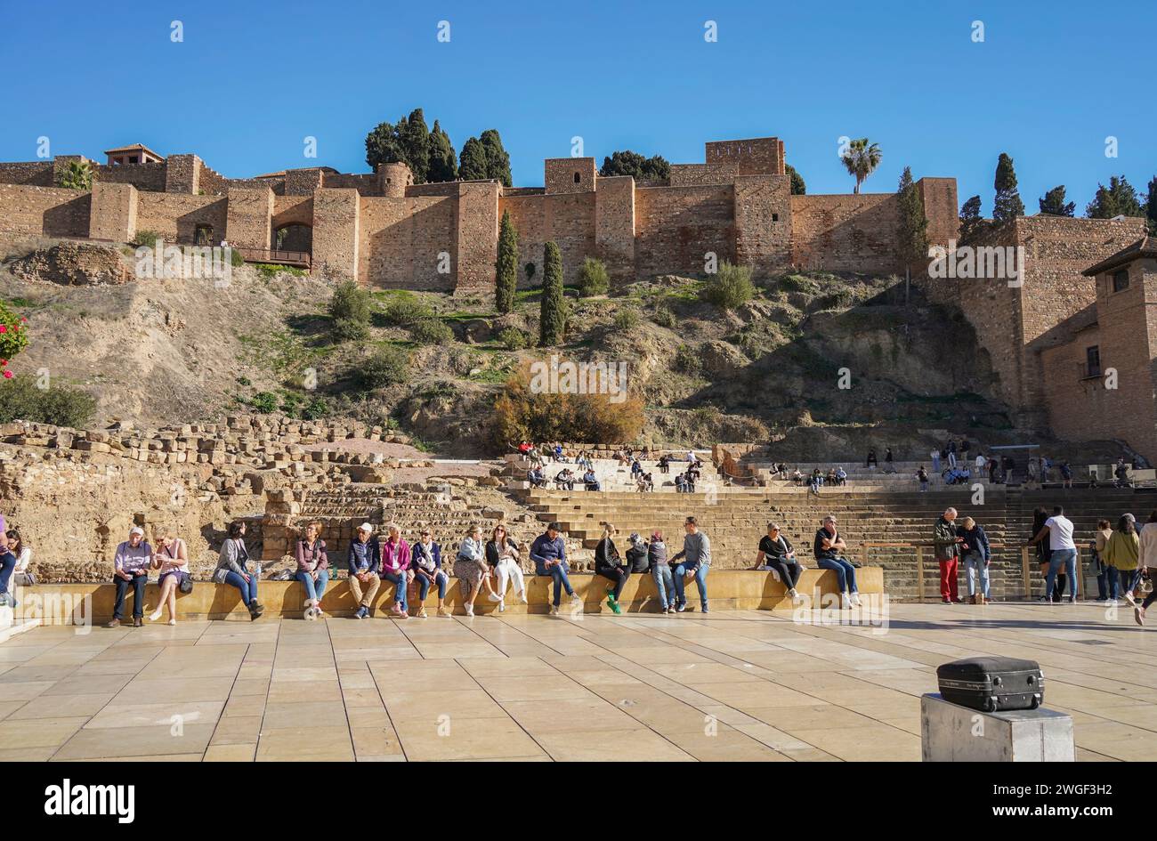 Malaga Spanien. Besucher vor Malaga Alcazaba. Altes römisches Amphitheater mit Schloss Alcazaba dahinter, Malaga, Andalusien, Spanien Stockfoto