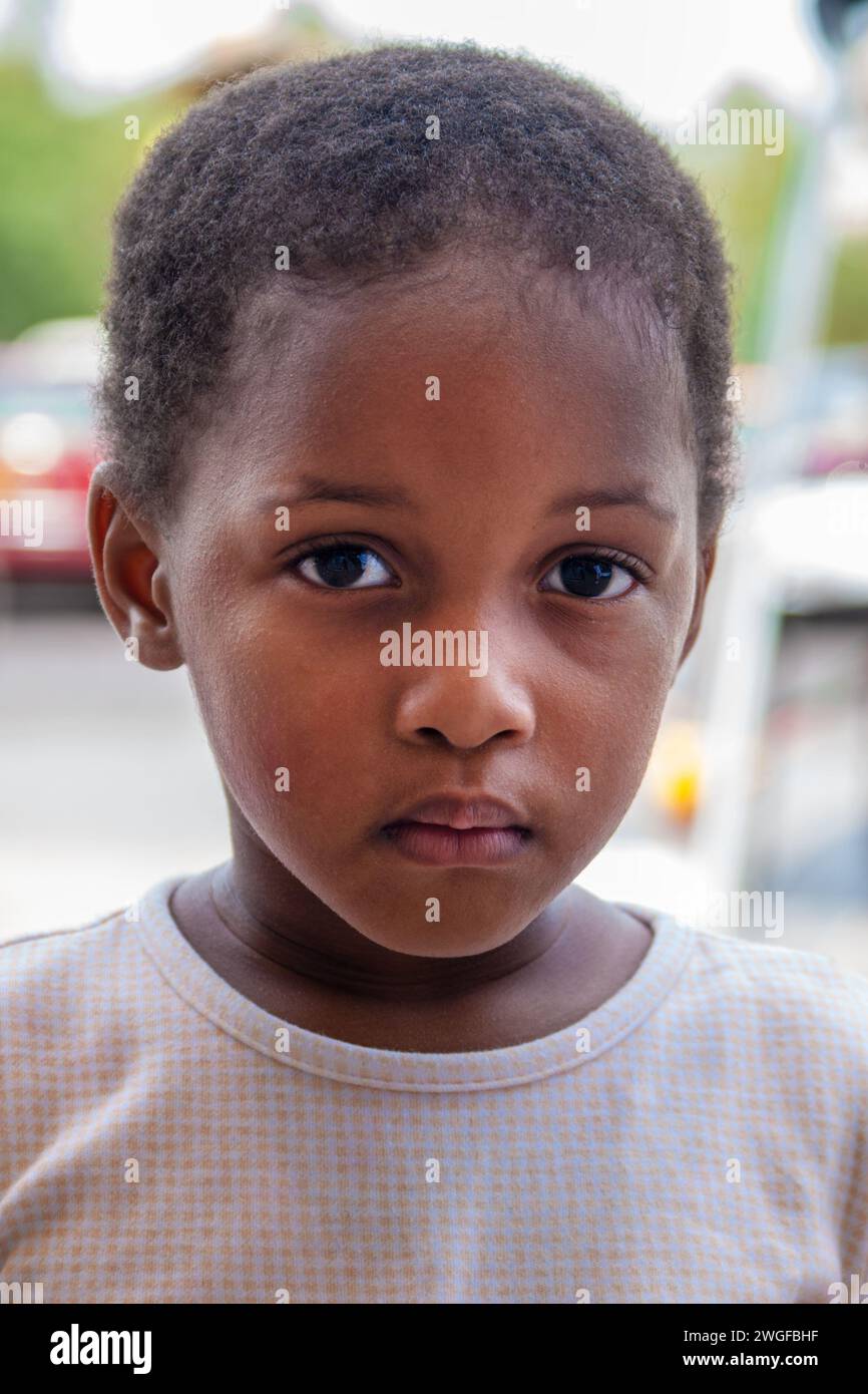 Porträt eines afrikanischen Mädchens, das auf der Straße steht, in einem Einkaufszentrum mit Autos parkt Stockfoto