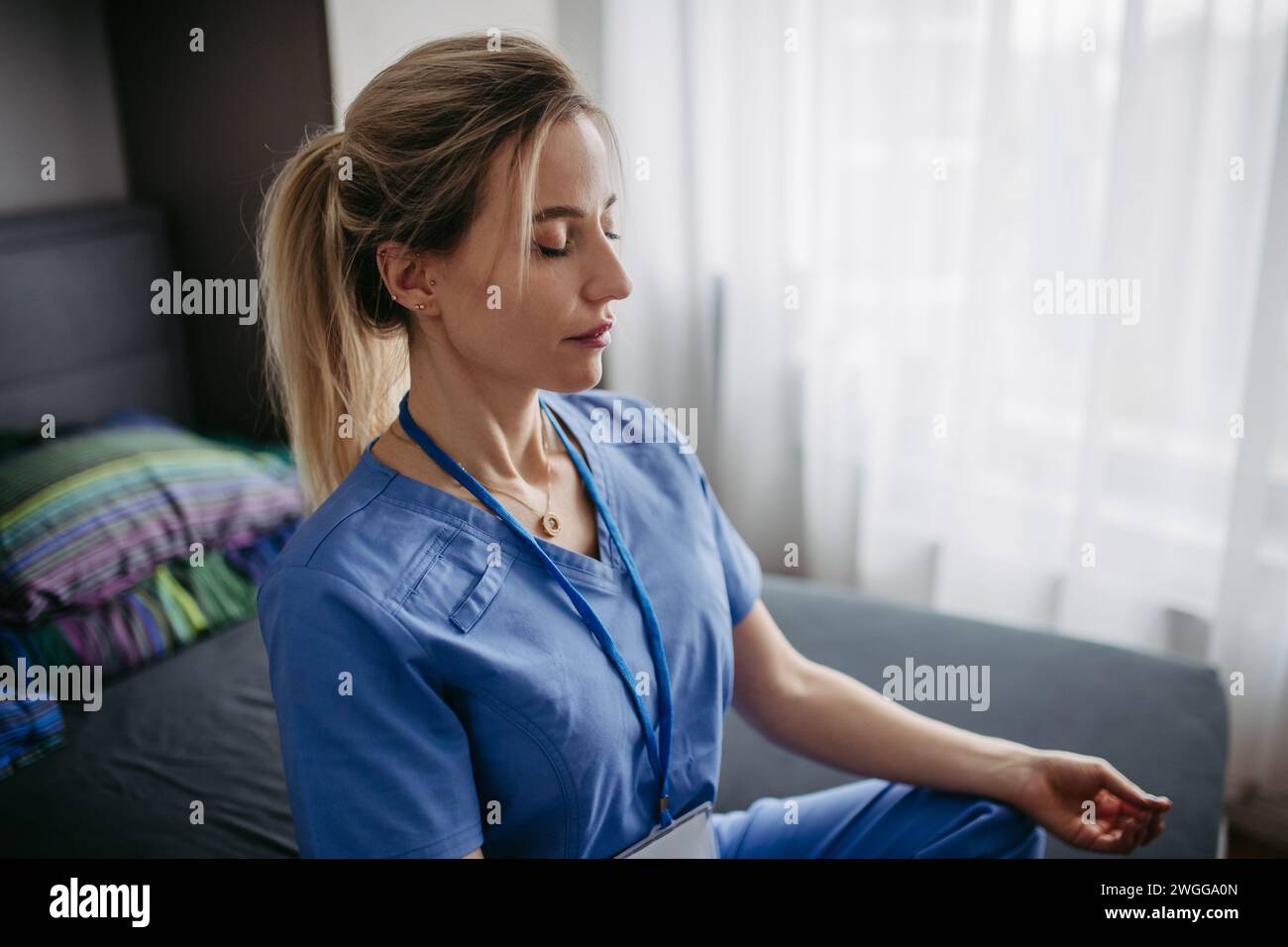 Nahaufnahme der Krankenschwester oder des Arztes, die nach der Arbeit Freizeit zu Hause genießen, Meditieren. Work-Life-Balance für eine Pflegekraft. Stockfoto