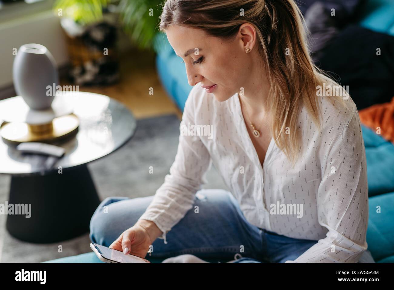 Krankenschwester oder Ärztin, die nach der Arbeit Freizeit zu Hause genießt. Porträt einer schönen Frau mit Smartphone in der Hand. Stockfoto