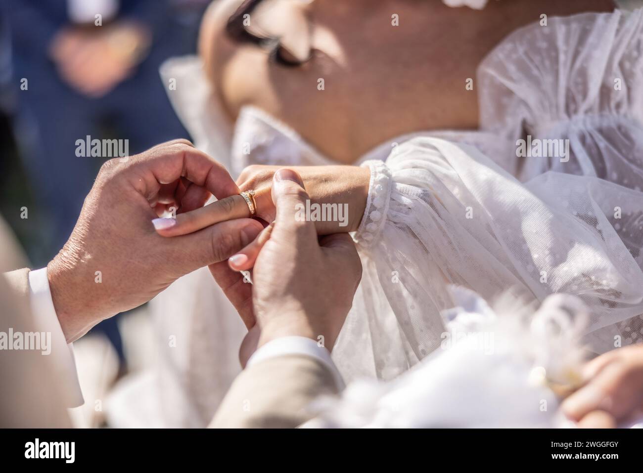 Detail des Bräutigams, der einen Ring an einen Finger der Braut legt. Stockfoto