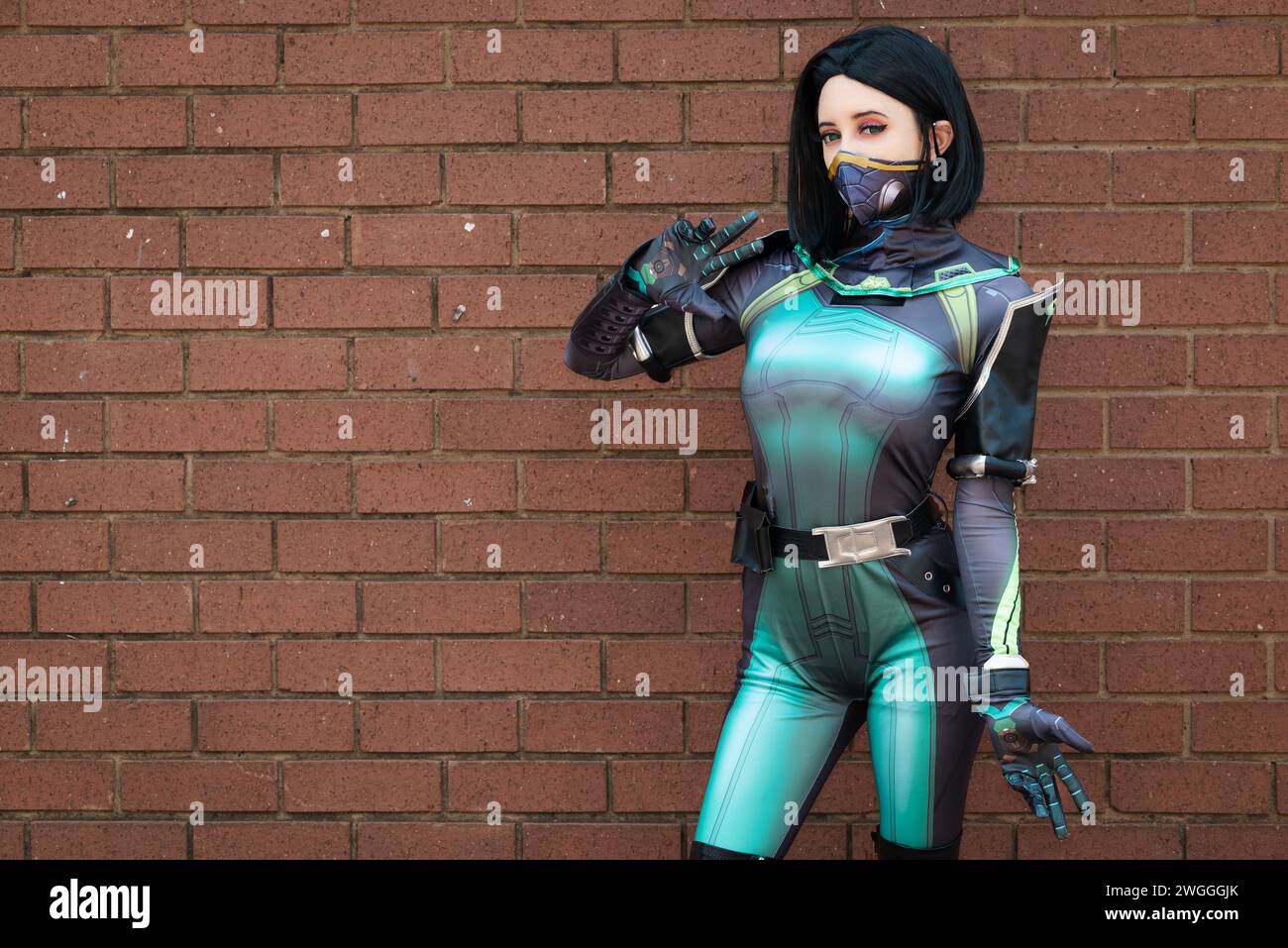Eine weibliche Cosplayer in einem grünen Action-Anzug gegen eine Ziegelwand Stockfoto