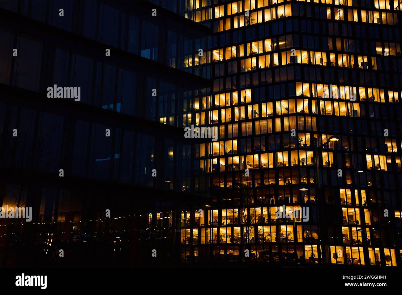 Außenansicht des Bürogebäudes mit leuchtenden Lichtern in den Fenstern in der nächtlichen Stadt. Wiener Innenstadt mit Wolkenkratzerfassaden. Nächtliches Stadtpanorama. Wor Stockfoto
