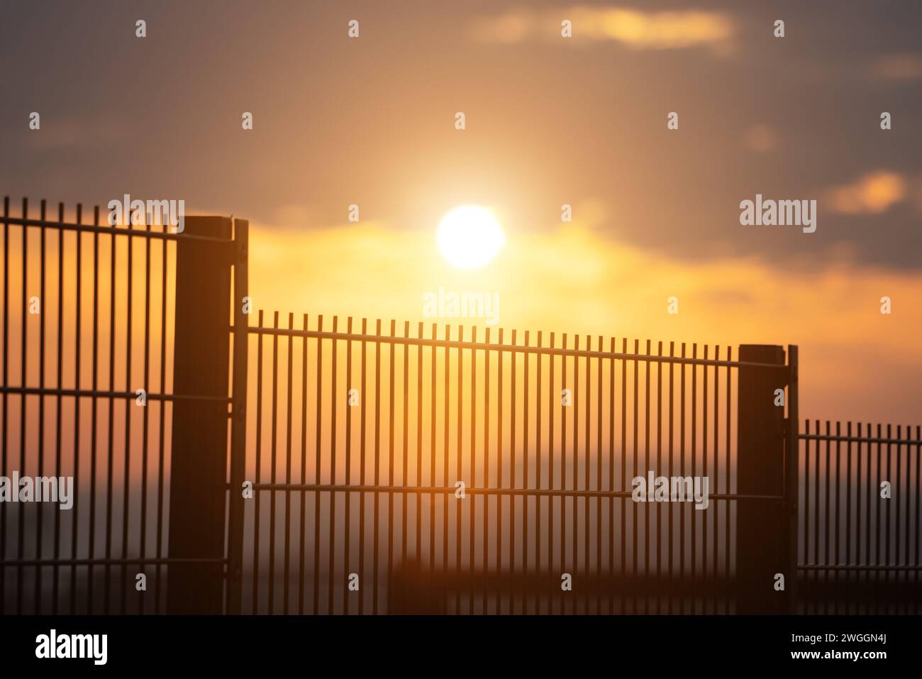 Sonnenaufgang vor dem Hintergrund eines Metallzauns Stockfoto