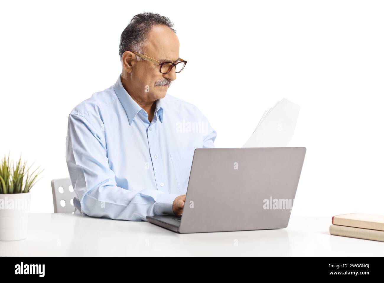 Reifer Mann, der an einem Schreibtisch sitzt und an einem Laptop arbeitet, isoliert auf weißem Hintergrund Stockfoto