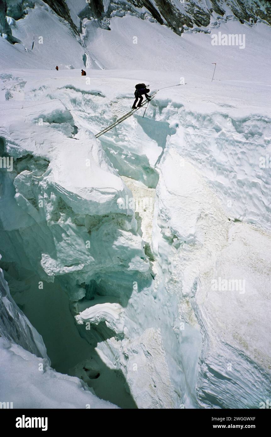 Ein Kletterer, der eine Leiter auf dem Khumbu-Eisfall hinunterfährt. Stockfoto