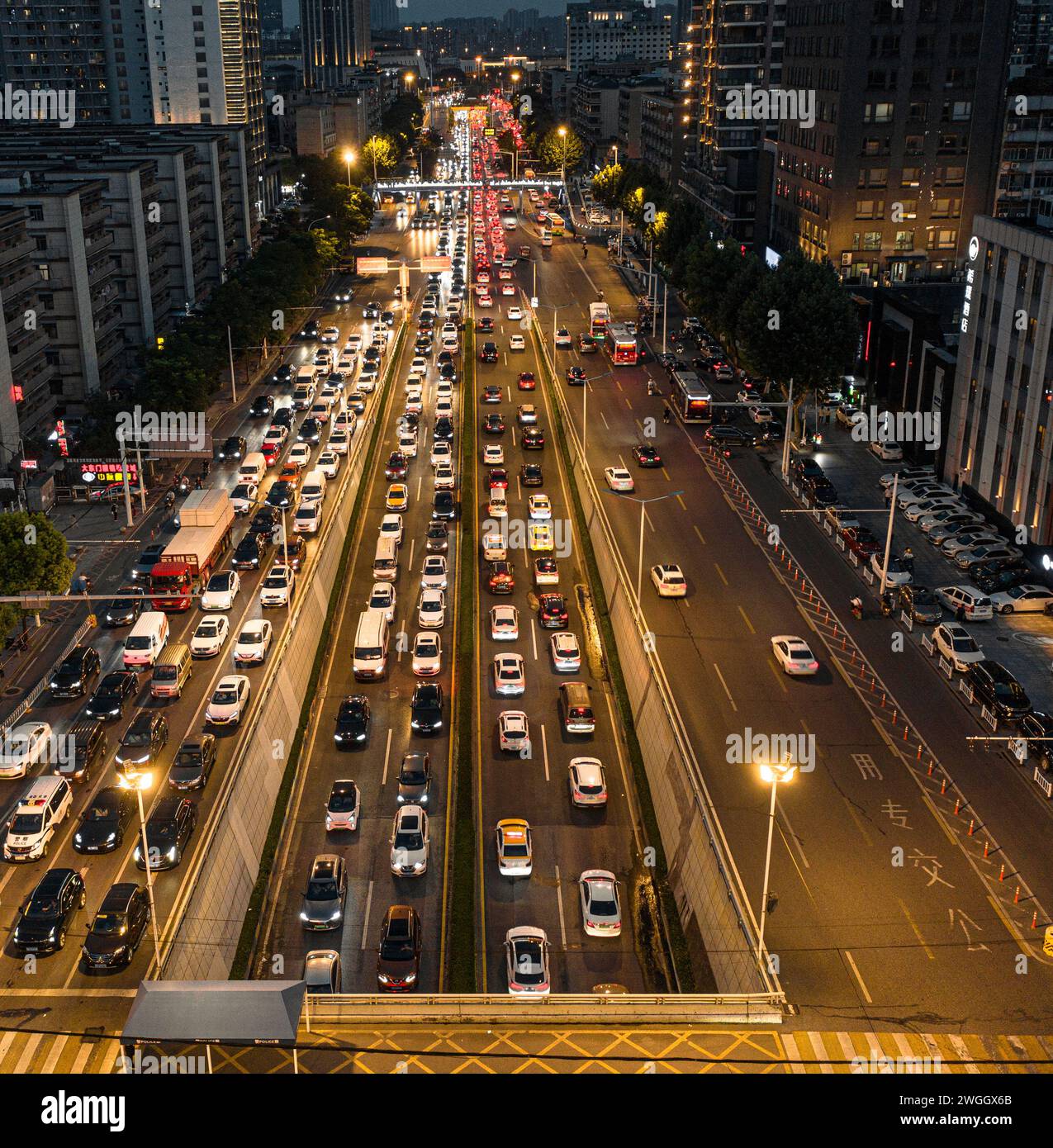 Die Kreuzung während der abendlichen Hauptverkehrszeit ist mit Fahrzeugen gefüllt. Über der Kreuzung befindet sich eine Fußgängerüberführung Stockfoto