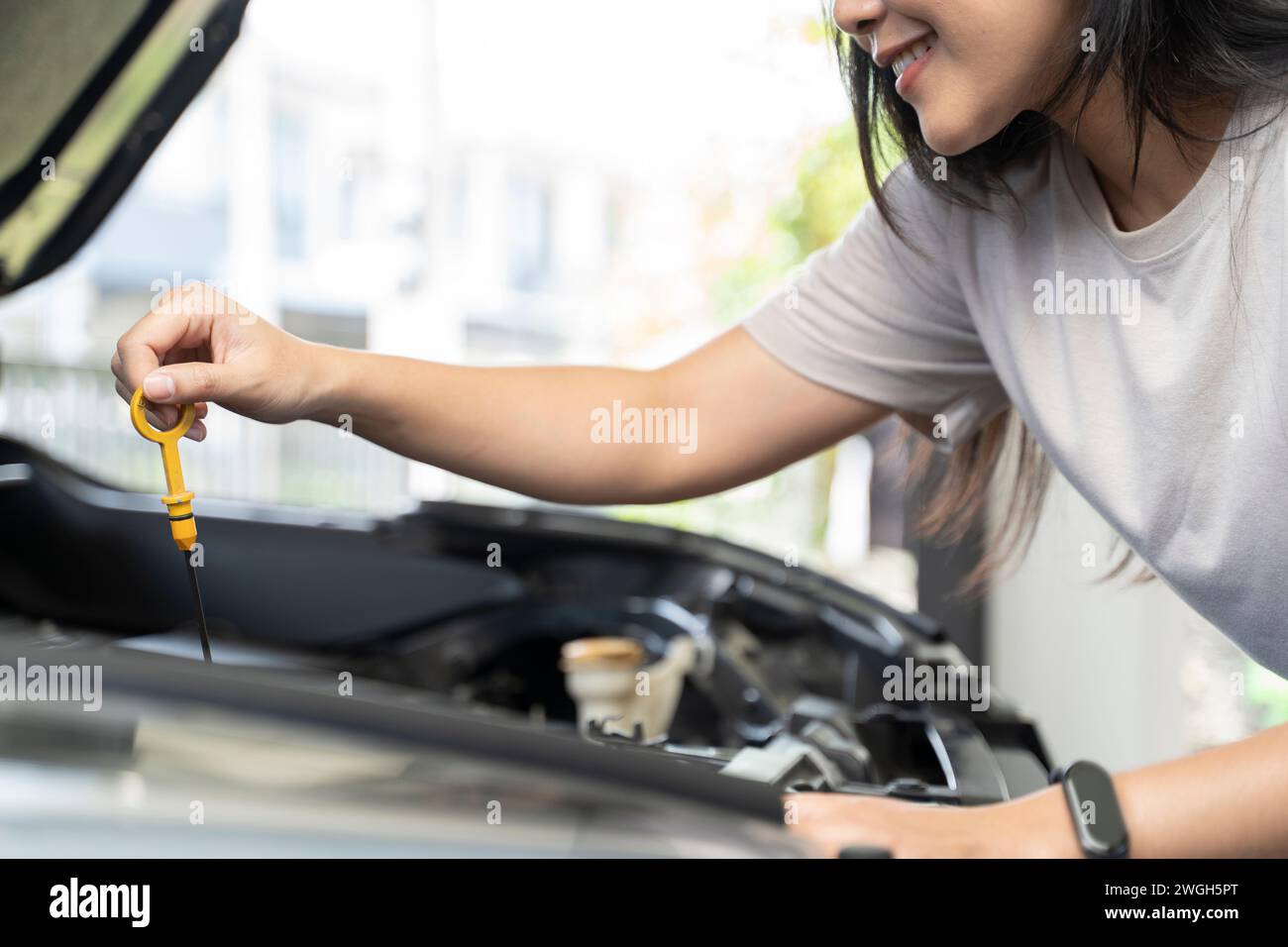 Frau, die neben einem Auto steht und den Motor überprüft. Stockfoto
