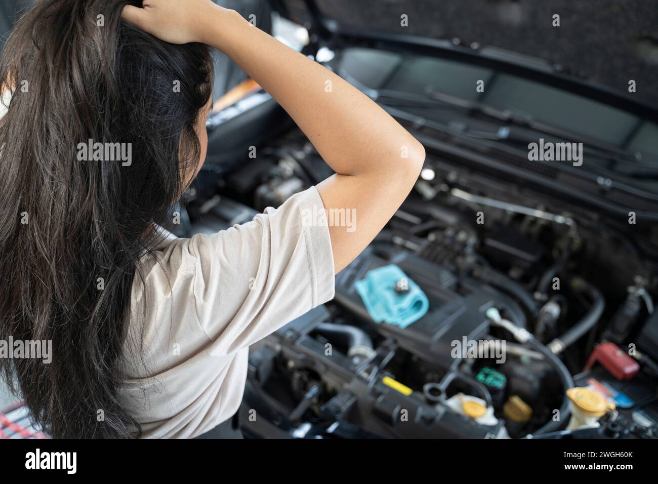 Asiatische Frau, die Probleme mit ihrem Auto hat schöne Frau, die kaputte Autos inspiziert, bevor sie zu Hause geht. Stockfoto