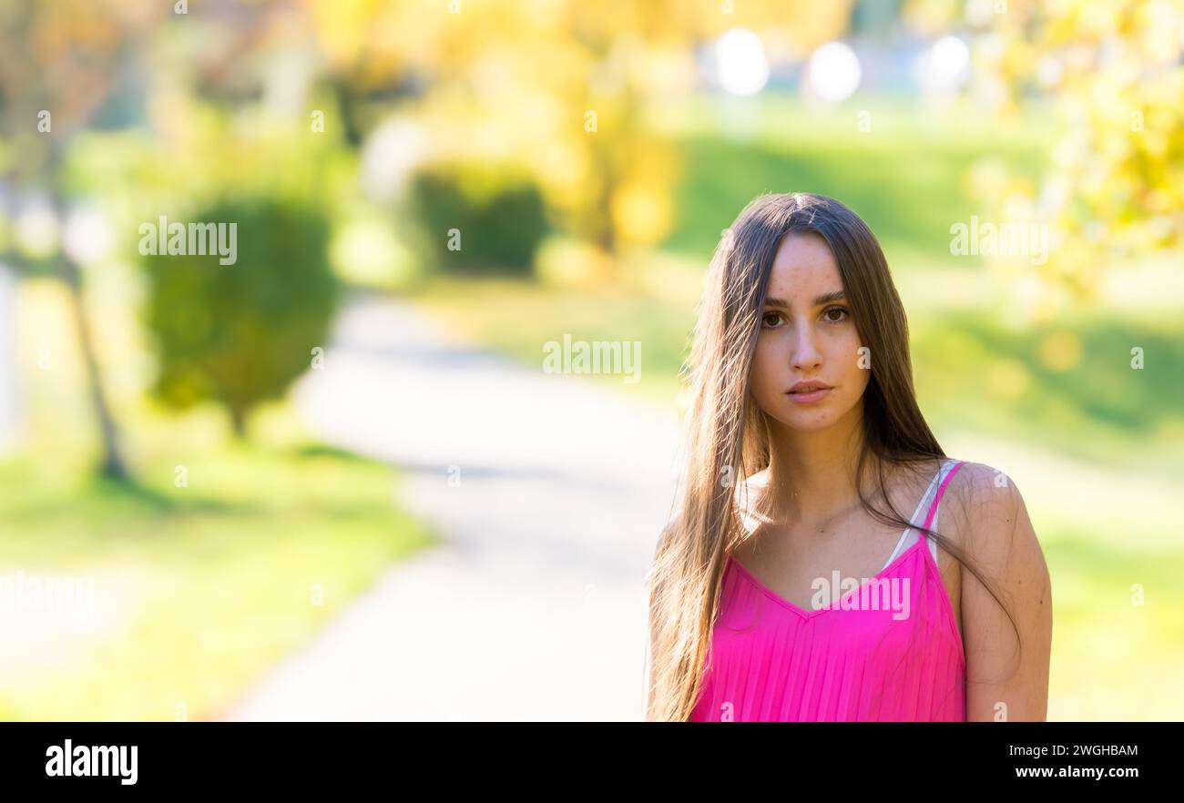 Besinnliche junge Frau mit langen braunen Haaren und gelbem Outfit Stockfoto