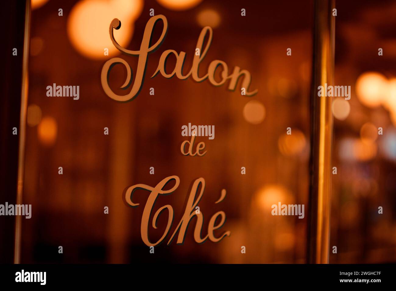 Elegantes Schriftstück auf dem Glasfenster mit dem Aufdruck „Salon de Thé“, das eine gemütliche, Vintage-Teestube-Atmosphäre vermittelt. Paris, Frankreich. Stockfoto