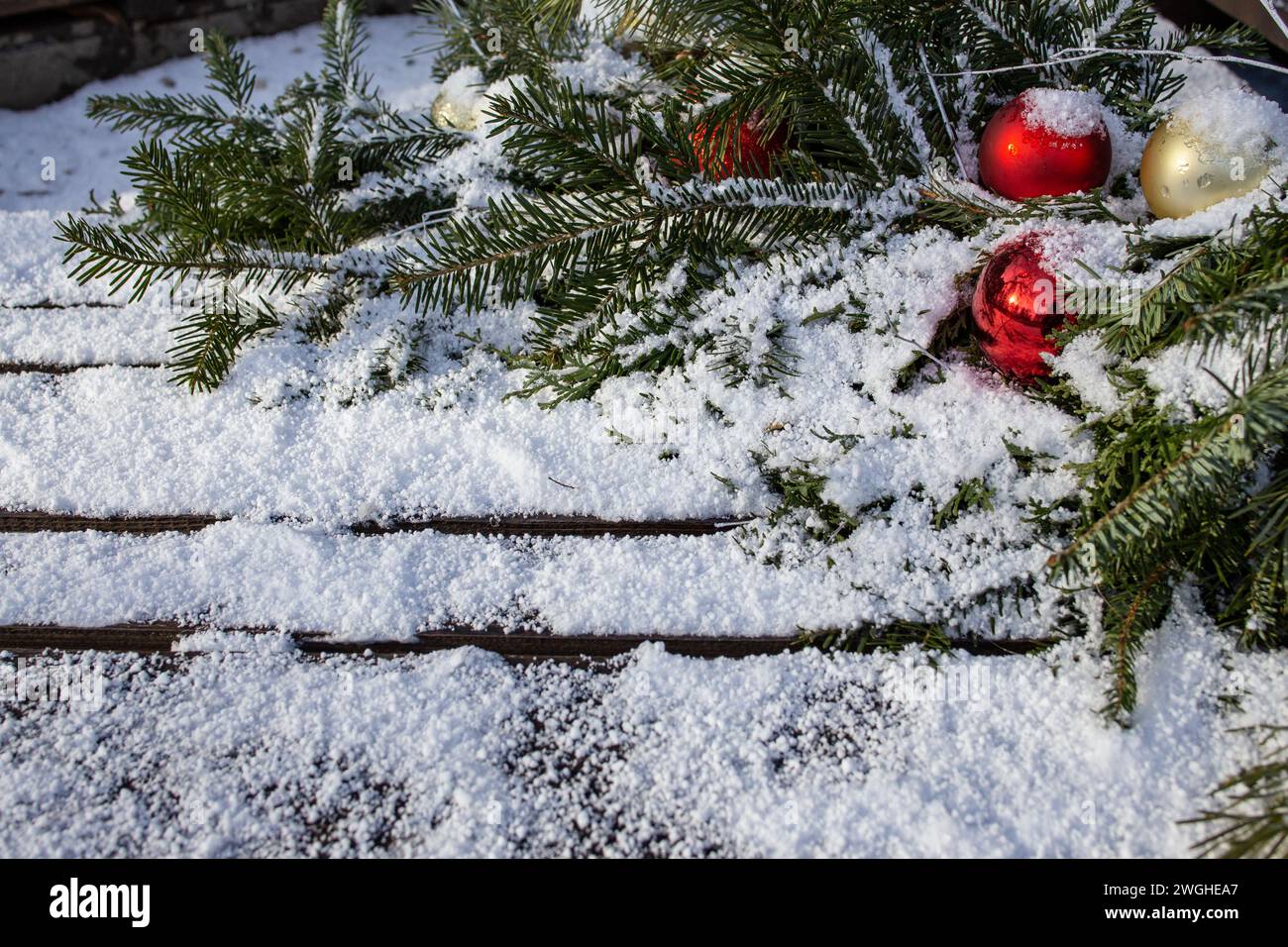 Rote weihnachtsbaumkugeln mit Tannenzweigen und echtem Schnee auf Holzbrettern Stockfoto